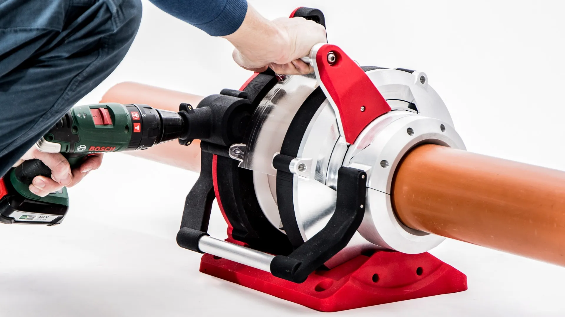 The ProCut pipe cutting tool clamped around a drainage pipe, driven by a cordless drill