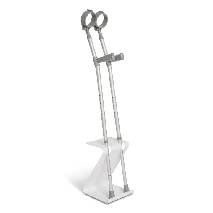 Stanza, a white self-supporting walking aid holder with a folded Z-shaped base, holding a pair of grey forearm crutches upright and within reach.